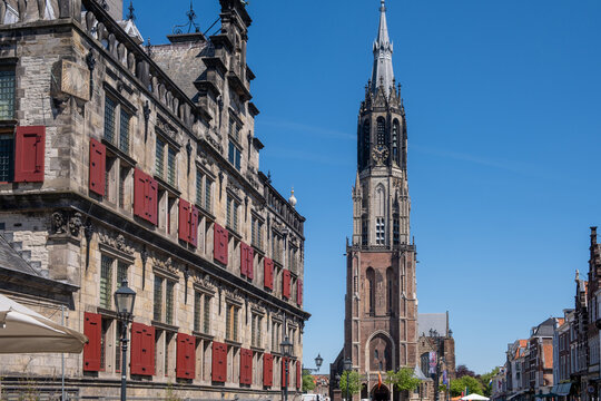 Historic buildings in Delft, Netherlands, Delft City Hall and the Gothic tower of Nieuwe Kerk, blue sky.