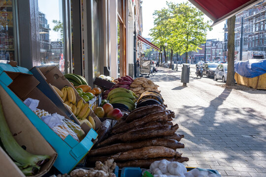 Fresh tropical produce displayed outside a neighborhood grocery on a sunny city sidewalk