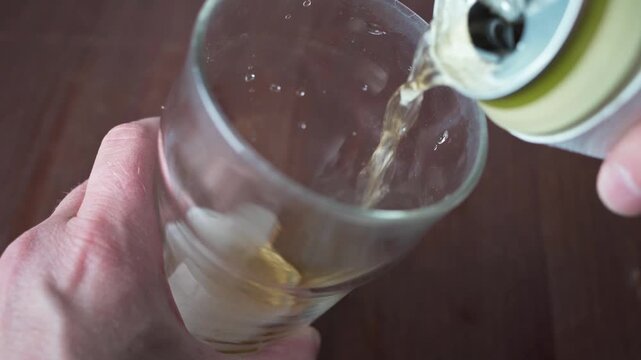 Pouring beer into pint glass on wooden table close up