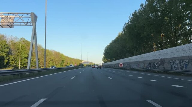 Amsterdam Netherlands highway, Sunny urban highway drive beside a tall sound barrier