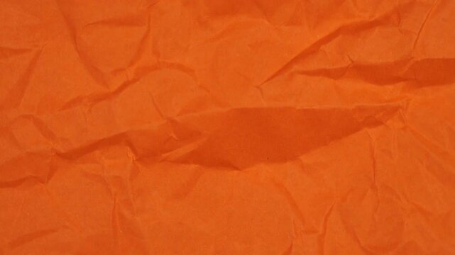 Rotation of crumpled orange sheet of paper