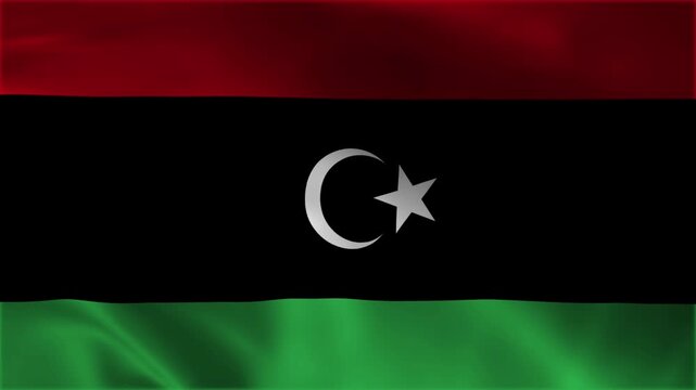 Libya national flag waving in loop seamless background video, close up of the libyan tricolor banner featuring a white crescent and star emblem on black red and green stripes graphic backdrop.
