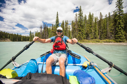 Happy young man rowing an inflatable raft on a river