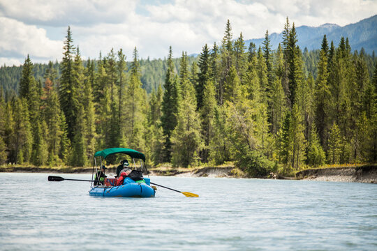 People in a blue raft float down a scenic river