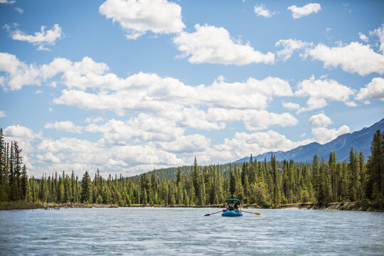 People paddle a raft down a beautiful mountain river
