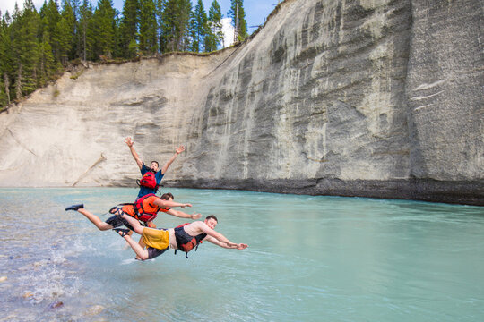 Three friends do a stacked dive into a river