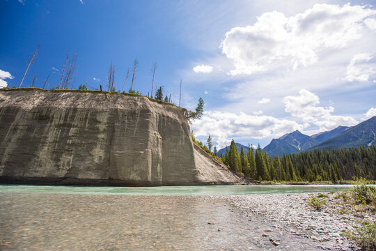 Turquoise mountain river flows past large silt bluffs