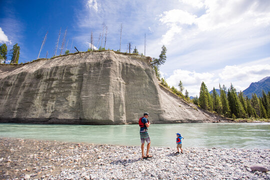 Father and son stand on a rocky river shore