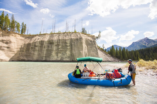 People launching an inflatable raft on a wilderness river
