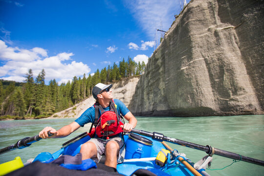 Man rows an inflatable raft down a scenic river
