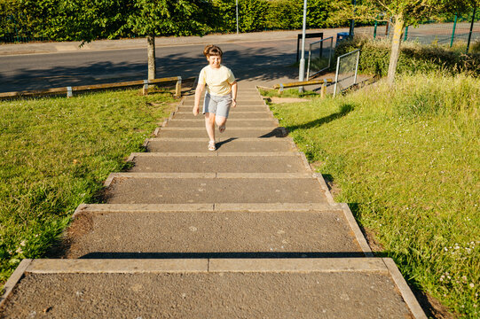 Child girl running up outdoor steps in residential park
