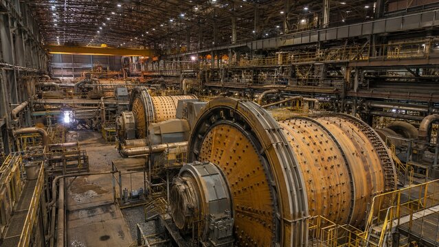 Interior of a massive copper concentrator plant featuring large rotating SAG and ball mills.