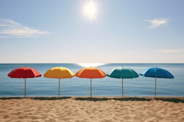 Fototapeta premium Five colorful umbrellas stand on a sandy beach under a bright sunny sky