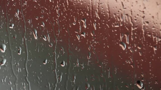 Rain water drop glass window wet condensation moisture transparent closeup with blurred background, soft lighting, natural texture, reflective surface, and moody calm atmosphere on window pane
