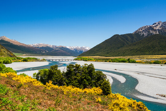 Scenic view of a braided river with a bridge and mountains