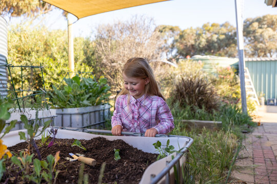 Child learning outdoor gardening under yellow canopy