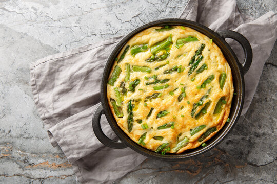 Keto diet asparagus frittata mea closeup in the skillet on the table. Horizontal top view from above