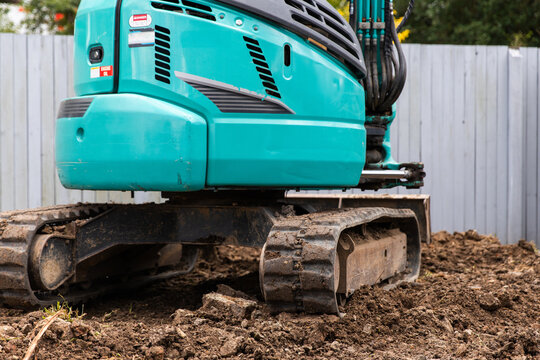 Excavator positioned on a mound of soil and rocks