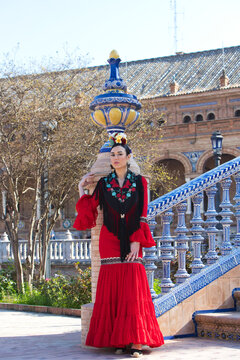 A beautiful woman dancing flamenco in a square in Seville, Spain. She is wearing a red ruffled dress and dances flamenco with great skill. Flamenco, a UNESCO Intangible Cultural Heritage.