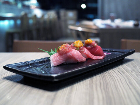 Fresh sliced raw tuna or otoro, chutoro and akami sushi sashimi topped with chopped tuna and uni sauce served with pickled wasab.