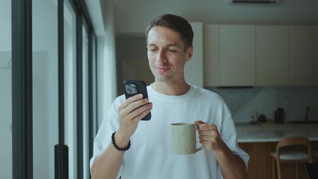 Man drinks coffee and scrolls smartphone enjoying comfort Comfort moment highlights comfort coziness and comfort of simple digital habits in modern home everyday lifestyle indoors morning time quietly