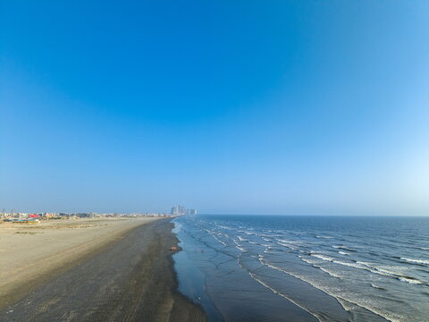 Aerial view of Sea-View Beach with its expansive sandy shoreline, gentle waves rolling onto the coast, and the distant city skyline in Karachi, Sindh, Pakistan.