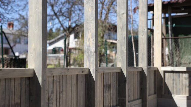 Gentle pan moves across interior framing, grey stained posts, tongue and groove panels, and tempered glass, with slight focus pull and strong diagonal shadows.