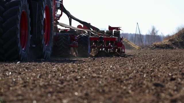 Low angle view shows large tractor and red multi disc cultivator cutting dry brown field, throwing dust and soil. Title appears. Utility pole and small vehicle sit near tree line.