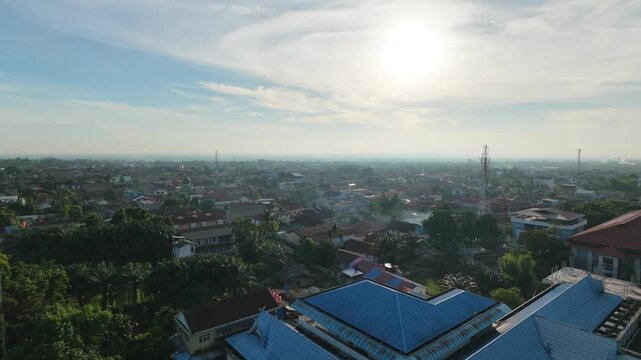 Cinematic aerial view of a small town in Indonesia, featuring residential neighborhoods, local roads, tropical greenery, and a peaceful community atmosphere.