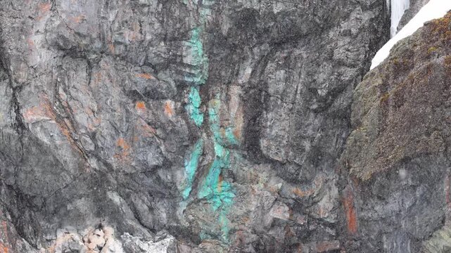 Copper vein in Antarctic rock, snowy day. Handheld