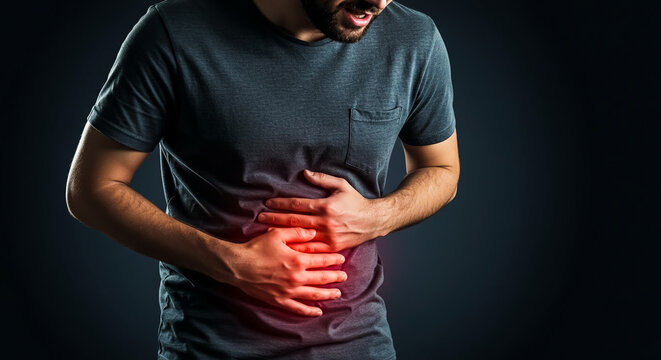 Young Caucasian man experiencing acute stomach pain, clutching his abdomen with a distressed express