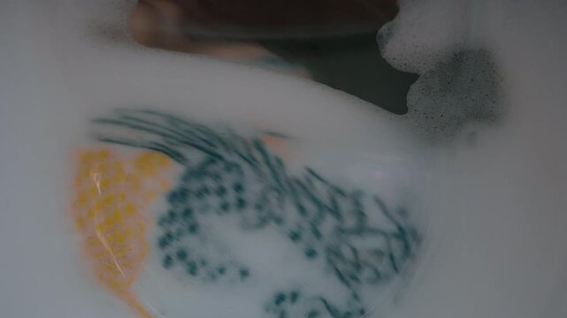 Clothing and soapy water spin around in machine. Washing machine door. Front loader