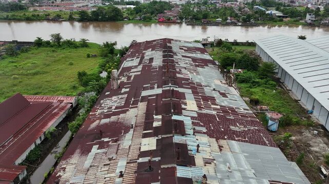 A view from above the Riverside factory, with its rusted metal roof and chimneys, as well as the surrounding natural landscape.