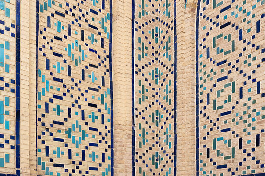 Geometric tilework detail on Kalyan Mosque in Bukhara featuring turquoise and cobalt glazed tiles set into sandy brickwork. Ideal for travel publications and cultural heritage materials.