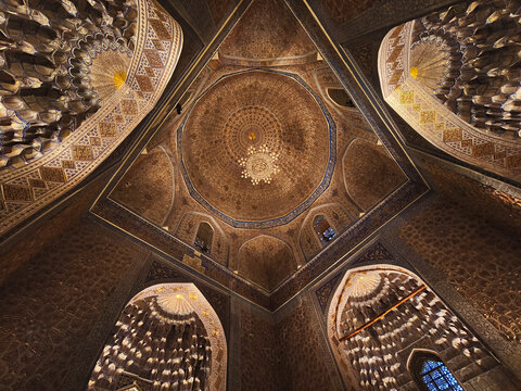 Ornate interior dome of Gur-e-Amir mausoleum in Samarkand featuring gilded muqarnas and geometric patterns. Ideal for travel publications, cultural heritage projects, and architectural studies.