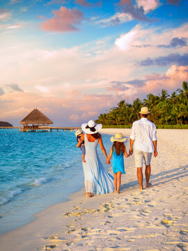 A beautiful family on vacations walks on a tropical paradise beach in the Maldives islands during sunset time