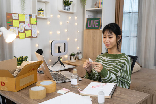 Cheerful Young Online Seller sits at desk preparing carefully organizing labels and packaging materials in Home Studio Workspace