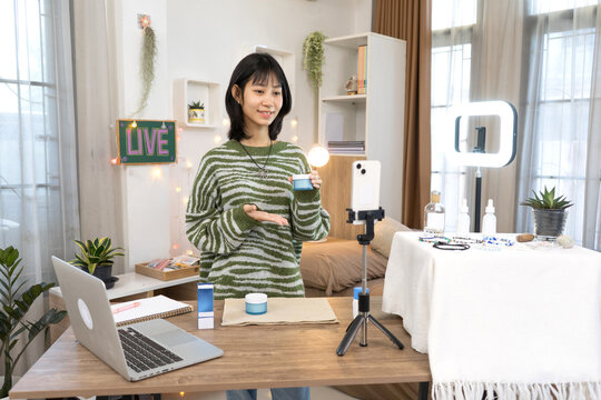 Young online seller presents skincare products during and demon strating live Commerce stream session in Home Studio