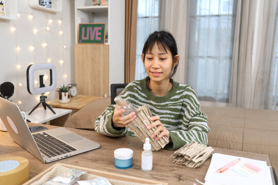 Young small business owner prepares product packaging for shipping online customer orders in home studio