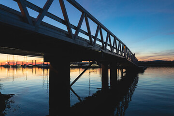 Fototapeta premium Modern aluminum alloy dock bridge in a river or lake at sunset