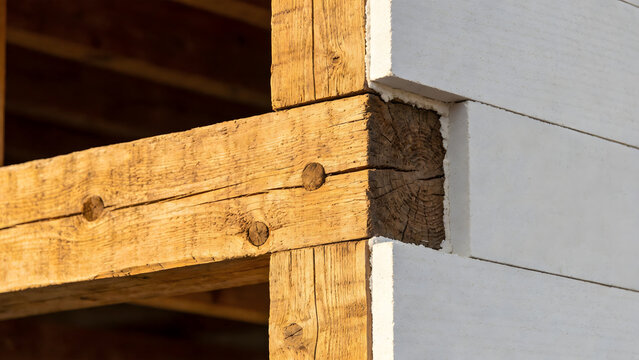 Architectural detail of exposed wooden joists against a plasterboard wall.