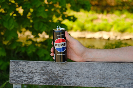 Man holding a Pepsi Zero Sugar aluminium can on a park bench. For beverage advertising, lifestyle branding, and casual outdoor campaigns. Prague - April 30, 2026.