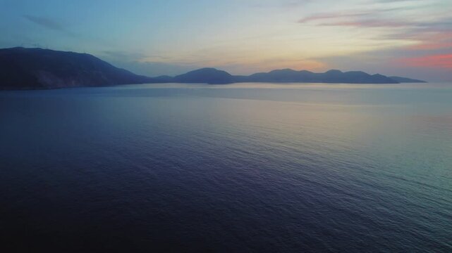 Soft pastel sunset over calm Mediterranean sea and distant islands