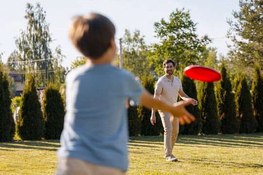 Father and son playing frisbee catching in backyard
