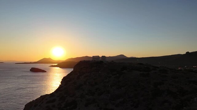 Cinematic 4K drone footage of the magnificent ancient Temple of Poseidon crowning the clifftops of Cape Sounion, offering a breathtaking perspective over the sparkling Mediterranean Sea, near Athens,