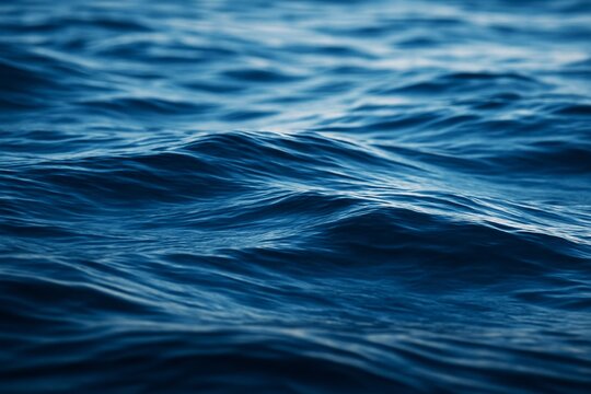 Close-up view of deep blue ocean waves with soft natural lighting and smooth textures, ideal for creative backgrounds and tranquil atmospheres. Ai generative