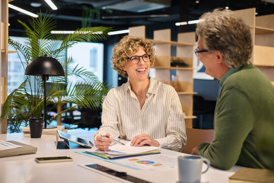 Happy mature businesswoman in friendly conversation with businessman
