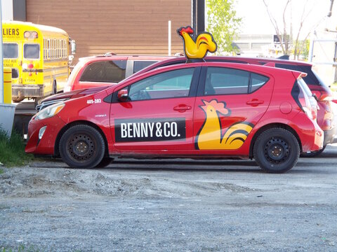 Gatineau,Quebec, Canada &ndash; May 16, 2026:A red "Benny and Co." branded car with a rooster topper is parked in an asphalt lot outside on Bd de la Carri&egrave;re.