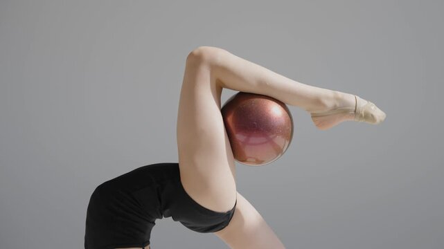 Little gymnast posing with a ball on a white background. 