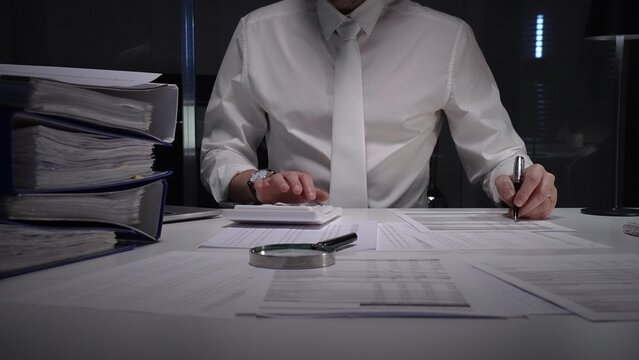 Business professional working late on financial audit in modern office, analyzing tax documents and managing paperwork deadlines with precision and expertise